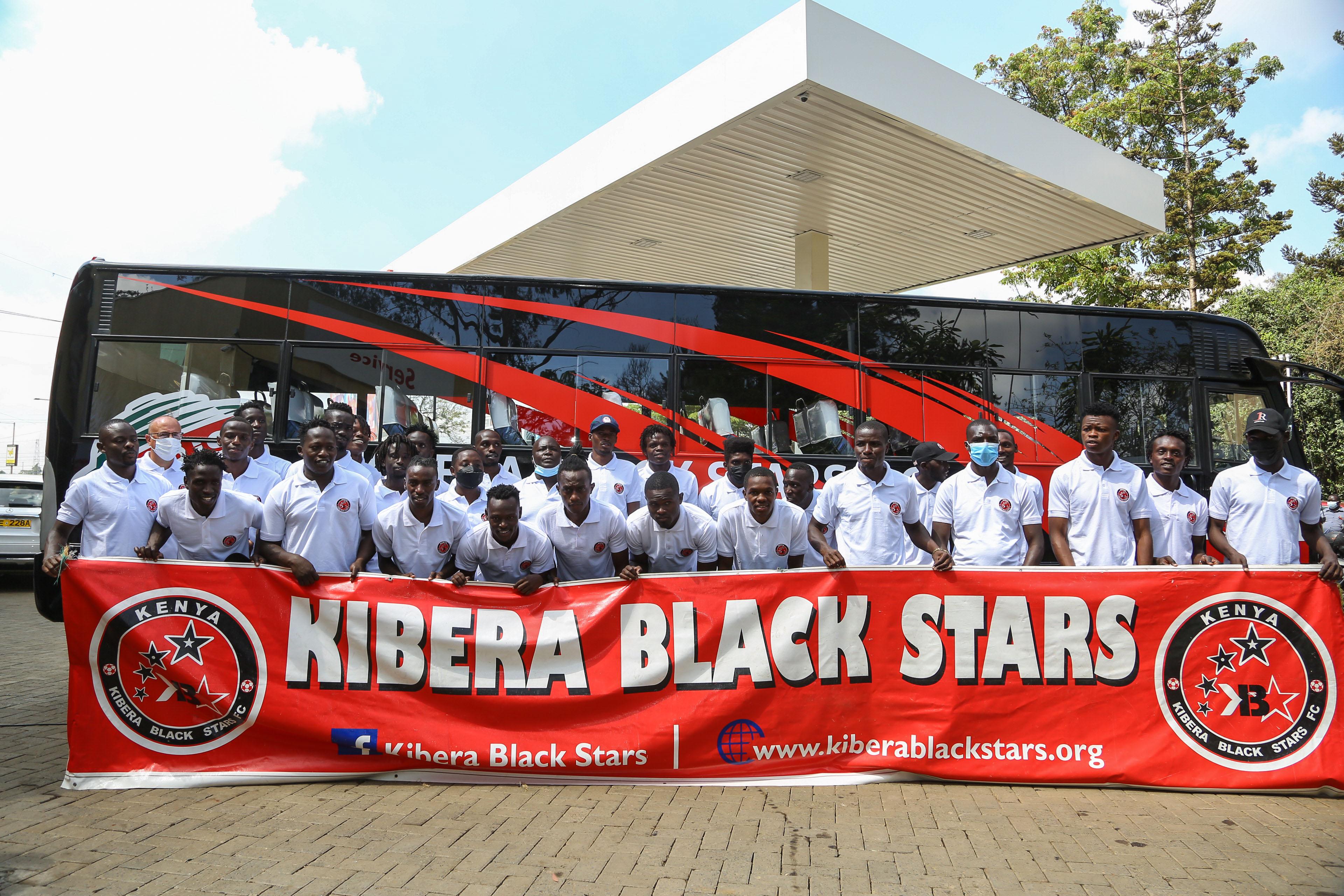 Kibera black stars association holding a banner with their name in front of a branded bus given by Rubis energy Kenya